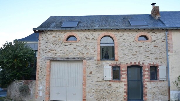 A stone building with a garage door, two arched windows, and a chimney. - Bed and Breakfast 'L'Isle Briand' with Wi-Fi (Montreuil-sur-Maine)