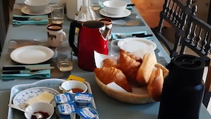 A dining table with plates, cutlery, a pitcher, a thermos, and food items. - Bed and Breakfast 'L'Isle Briand' with Wi-Fi (Montreuil-sur-Maine)