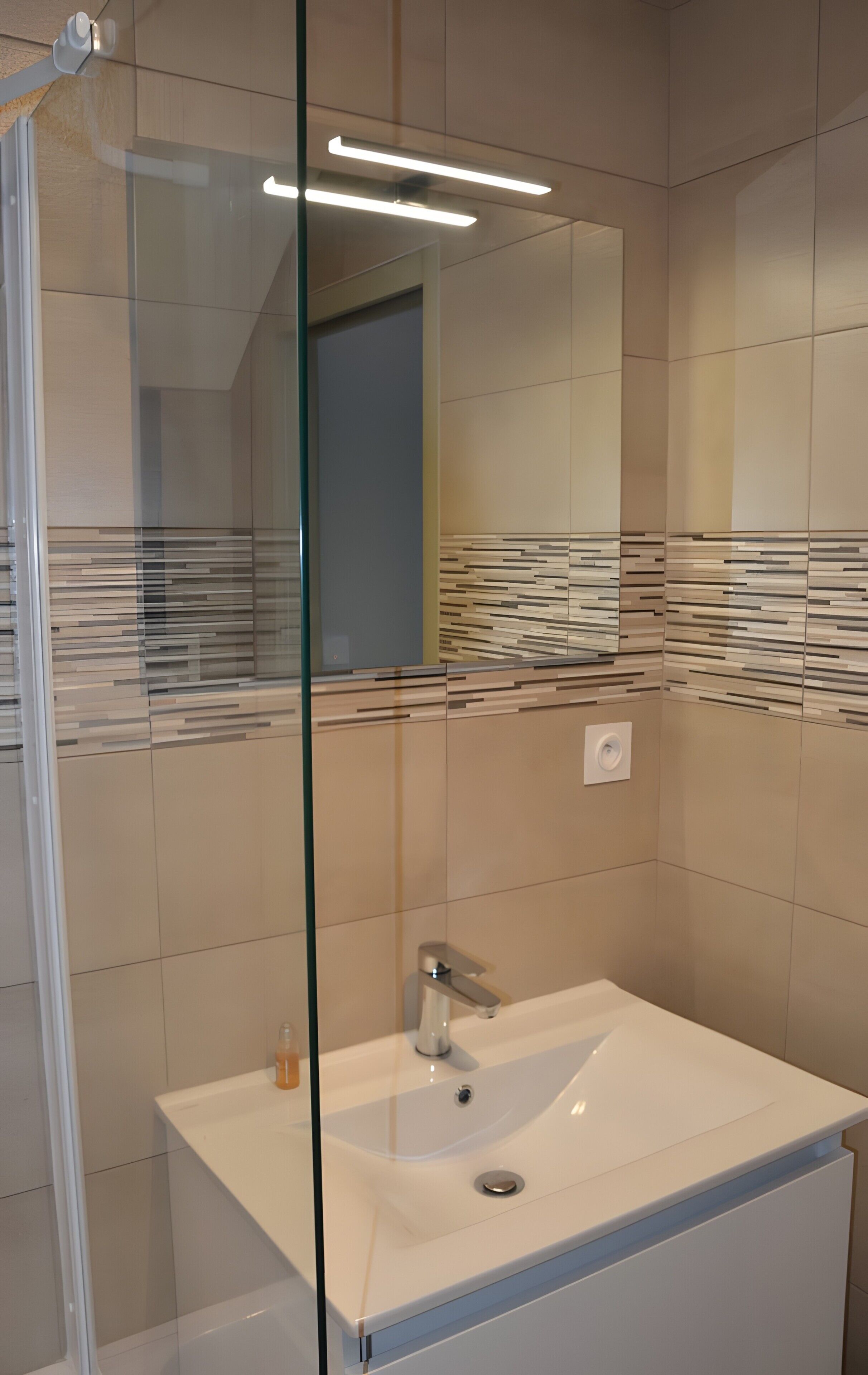 A modern bathroom with a glass partition, a white sink, and a mirror.