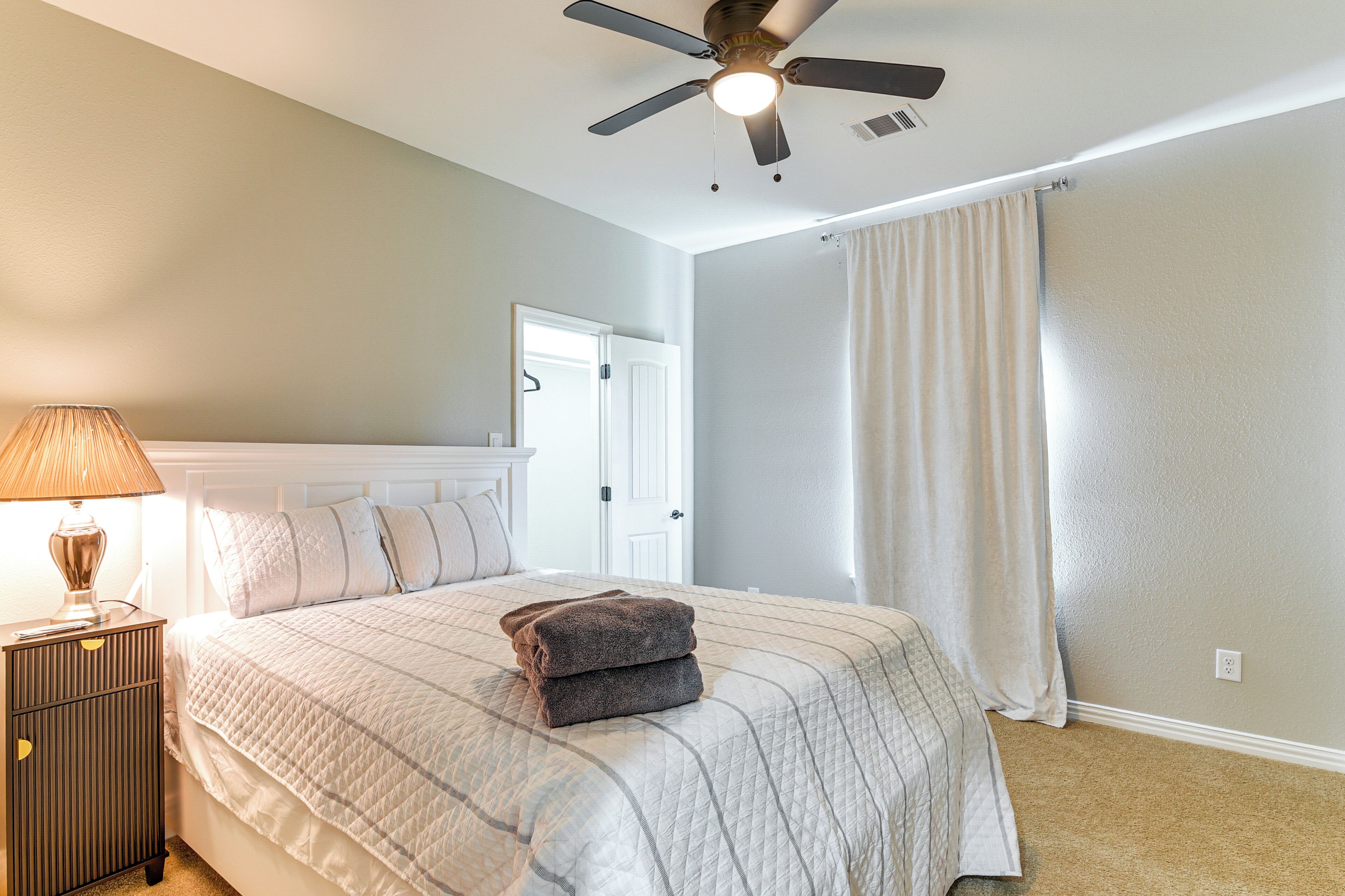 A neatly made bed with a quilted bedspread, a bedside lamp, and a folded towel on the bed.