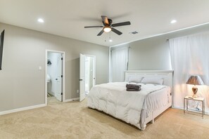 A bedroom with a bed, a ceiling fan, a bedside lamp, and a door leading to another room. - Easy Hwy Access to Dtwn: Pet-friendly Houston Home (Houston)