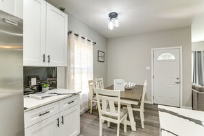 A modern kitchen with white cabinets, a dining table with chairs, and a white door. - Easy Hwy Access to Dtwn: Pet-friendly Houston Home (Houston)