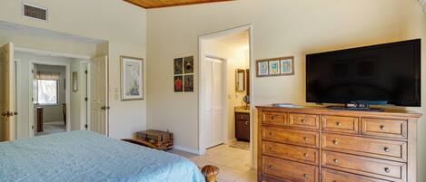 Une chambre à coucher comprenant un lit, une commode, un téléviseur et des œuvres d’art accrochées au mur.