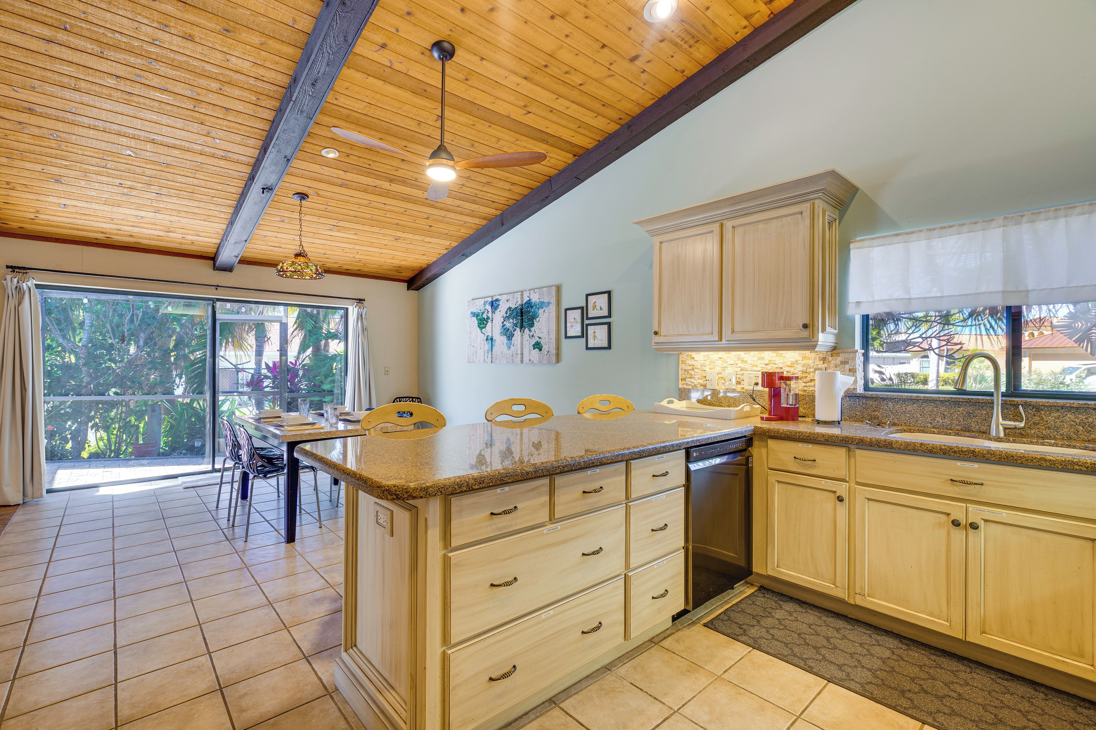 A spacious kitchen with wooden cabinets, a large island with a sink, and a dining area with a table and chairs.