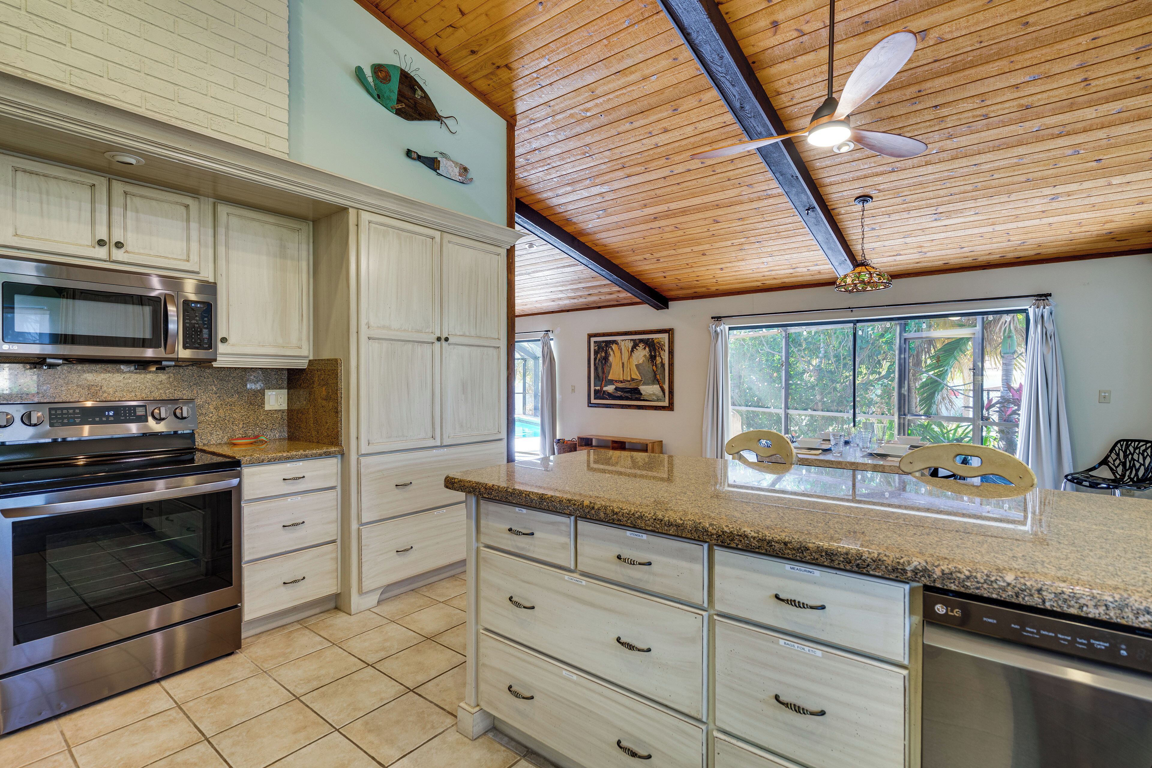 A kitchen with white cabinets, stainless steel appliances, a granite countertop, and a ceiling fan.