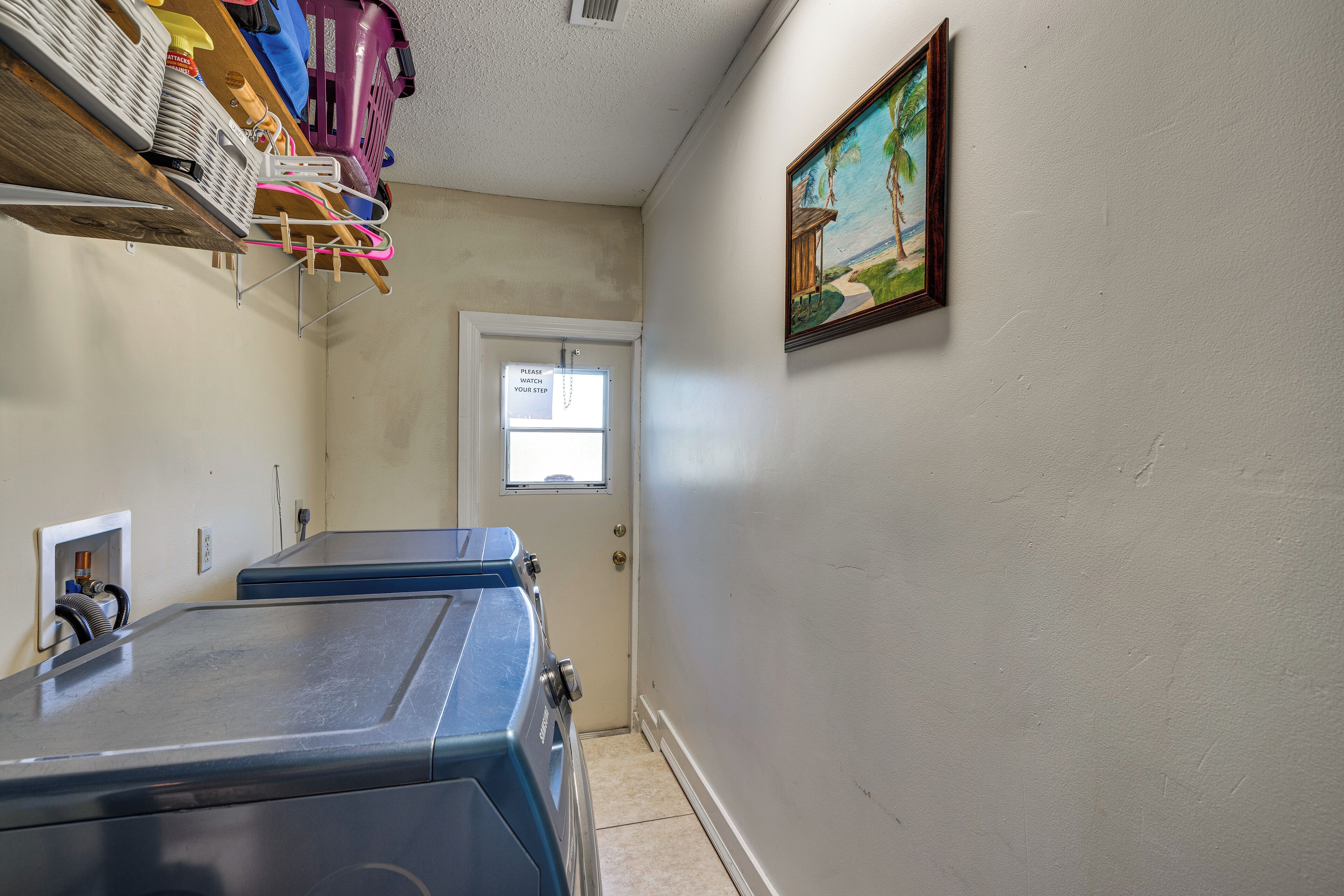 Un cuarto de lavandería con cestas de ropa apiladas, una puerta con un letrero y un cuadro en la pared.