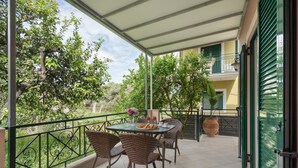 A balcony with wicker chairs, a table with a plate of food, and a potted plant. - Anna's One-Bedroom Apartment with Balcony, Wi-Fi and Air Conditioning (Νικιάνα)