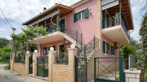 A two-story house with a balcony, a gated entrance, and a staircase leading to the upper floor. - Anna's One-Bedroom Apartment with Balcony, Wi-Fi and Air Conditioning (Νικιάνα)
