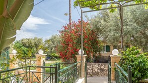 A garden with a metal railing, potted plants, and a stone wall. - Anna's Two-Bedroom Apartment with Mountain View, Wi-Fi, and Air Conditioning (Νικιάνα)