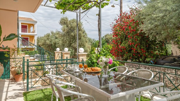 An outdoor patio with a glass-top table, wicker chairs, and a potted plant. - Anna's Two-Bedroom Apartment with Mountain View, Wi-Fi, and Air Conditioning (Νικιάνα)