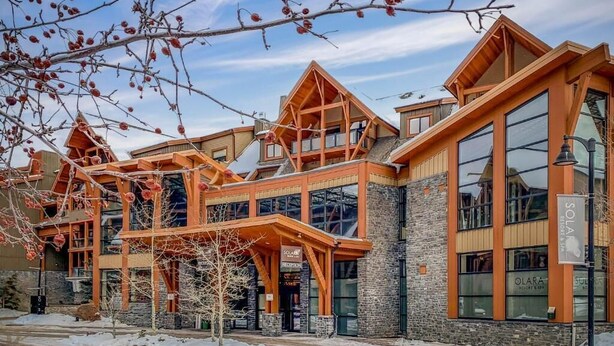 A modern building with a ski resort sign, large windows, and wooden architectural elements. - Solara 2BR Retreat Pool- Hot Tub -113 (Canmore)