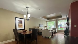 A spacious living room with a dining area, large windows, and a chandelier. - Solara 2BR Retreat Pool- Hot Tub -113 (Canmore)