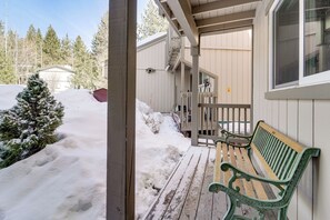 Eine Holzterrasse mit einer Bank, einem verschneiten Pfad und einem Gebäude mit Veranda.