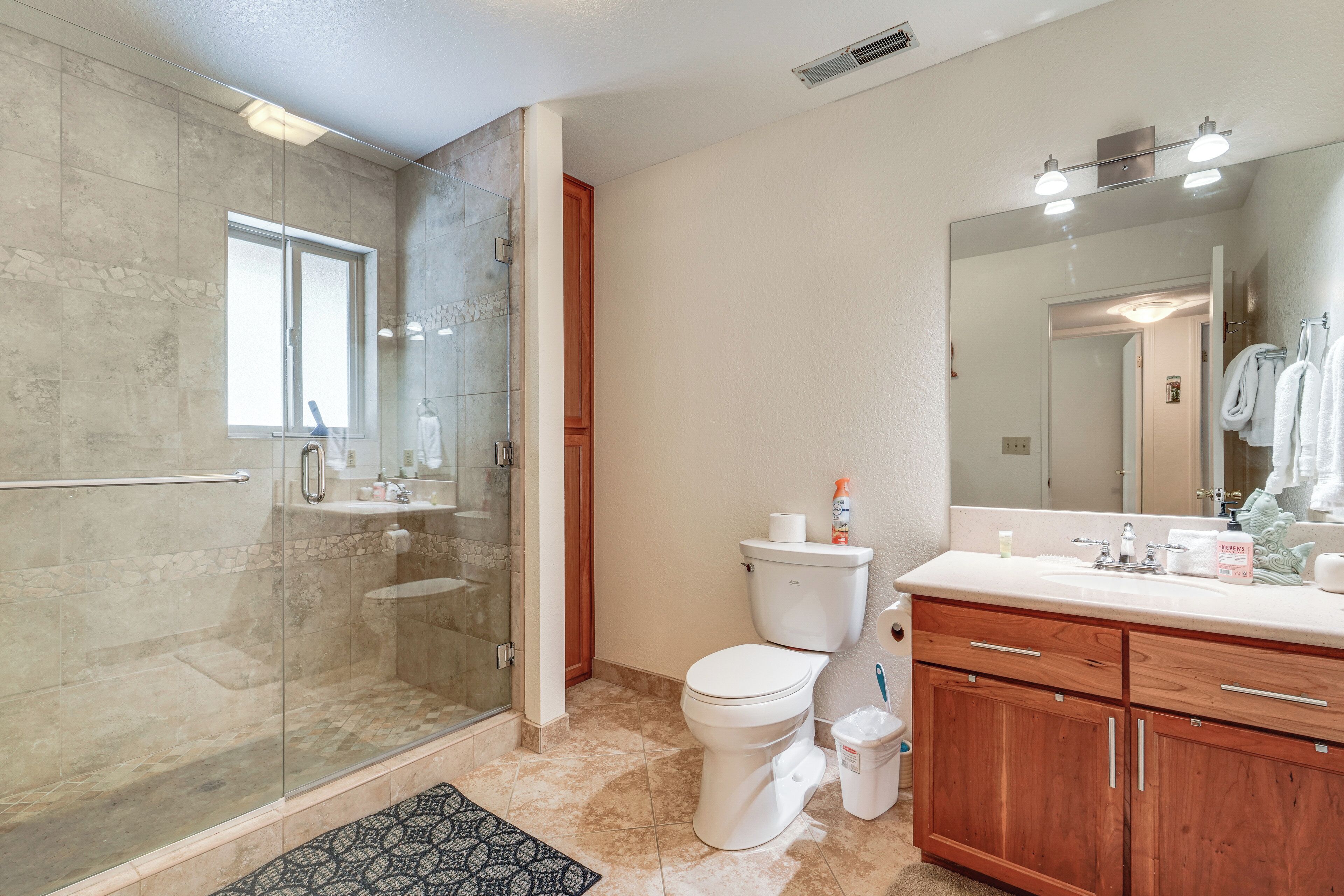 Een moderne badkamer met een douche met glazen wand, een toilet en een wastafel met een grote spiegel.