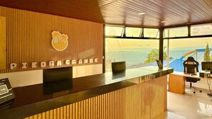 A reception desk with a wooden panel design and a view of mountains through large windows. - hotel piedra grande (San Antonio del Tequendama)