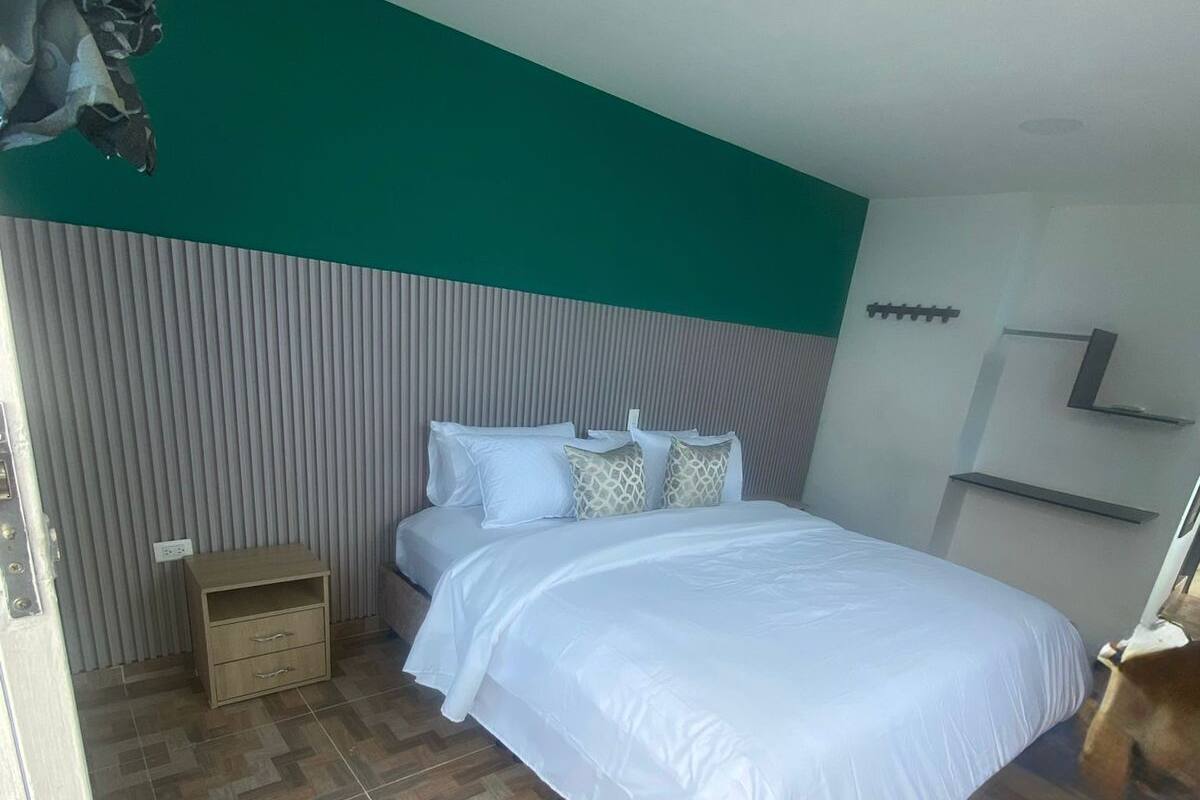 Een slaapkamer met een bed, een nachtkastje, een dressoir en een spiegel.