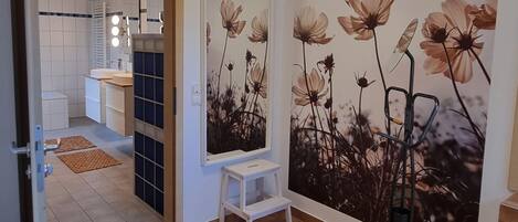 Un baño moderno con lavamanos blanco, espejo y suelo de baldosas.