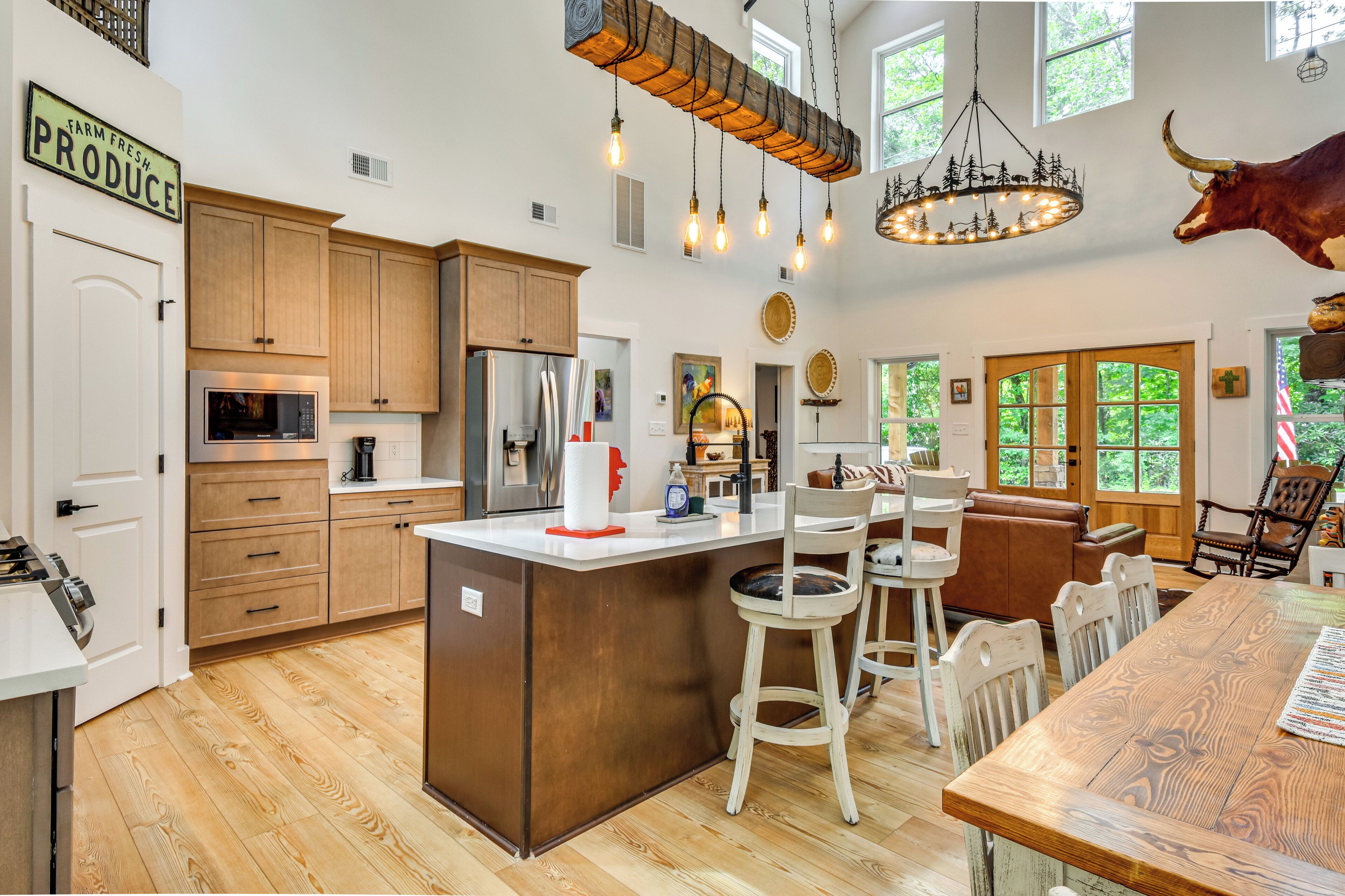 A spacious kitchen with wooden cabinets, a central island, and a hanging light fixture.