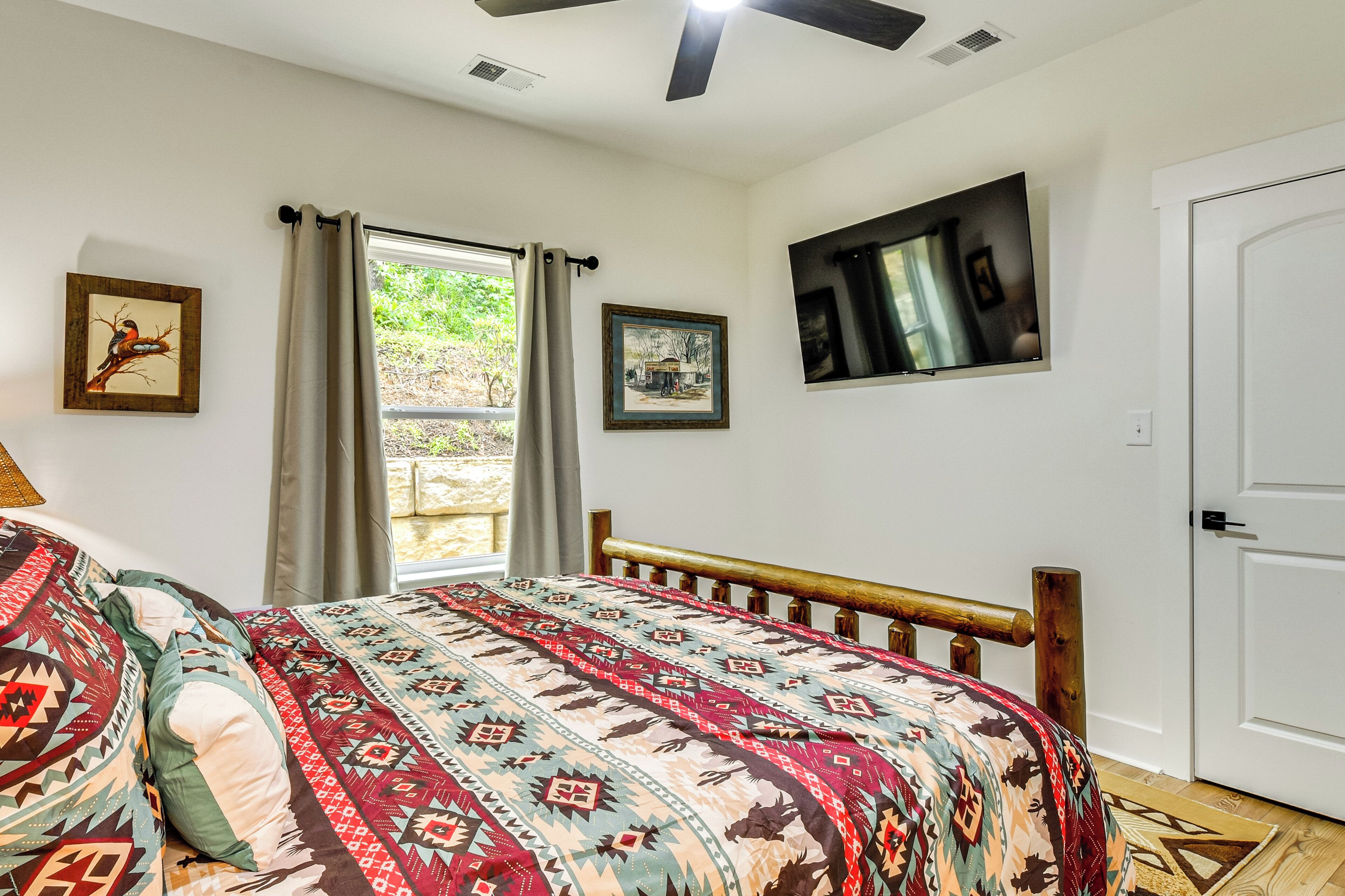 A bedroom with a wooden bed, a window with curtains, and artwork on the walls.