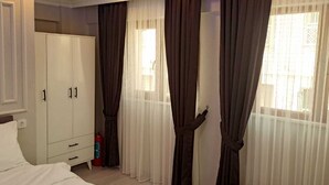Quarto com cama, guarda-roupa e janela com cortinas.