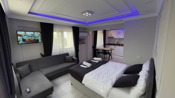 Quarto de hotel moderno com cama, sofá e pequena área de jantar.