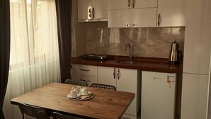 Uma cozinha compacta com uma mesa de madeira, duas cadeiras, uma pia e uma geladeira.