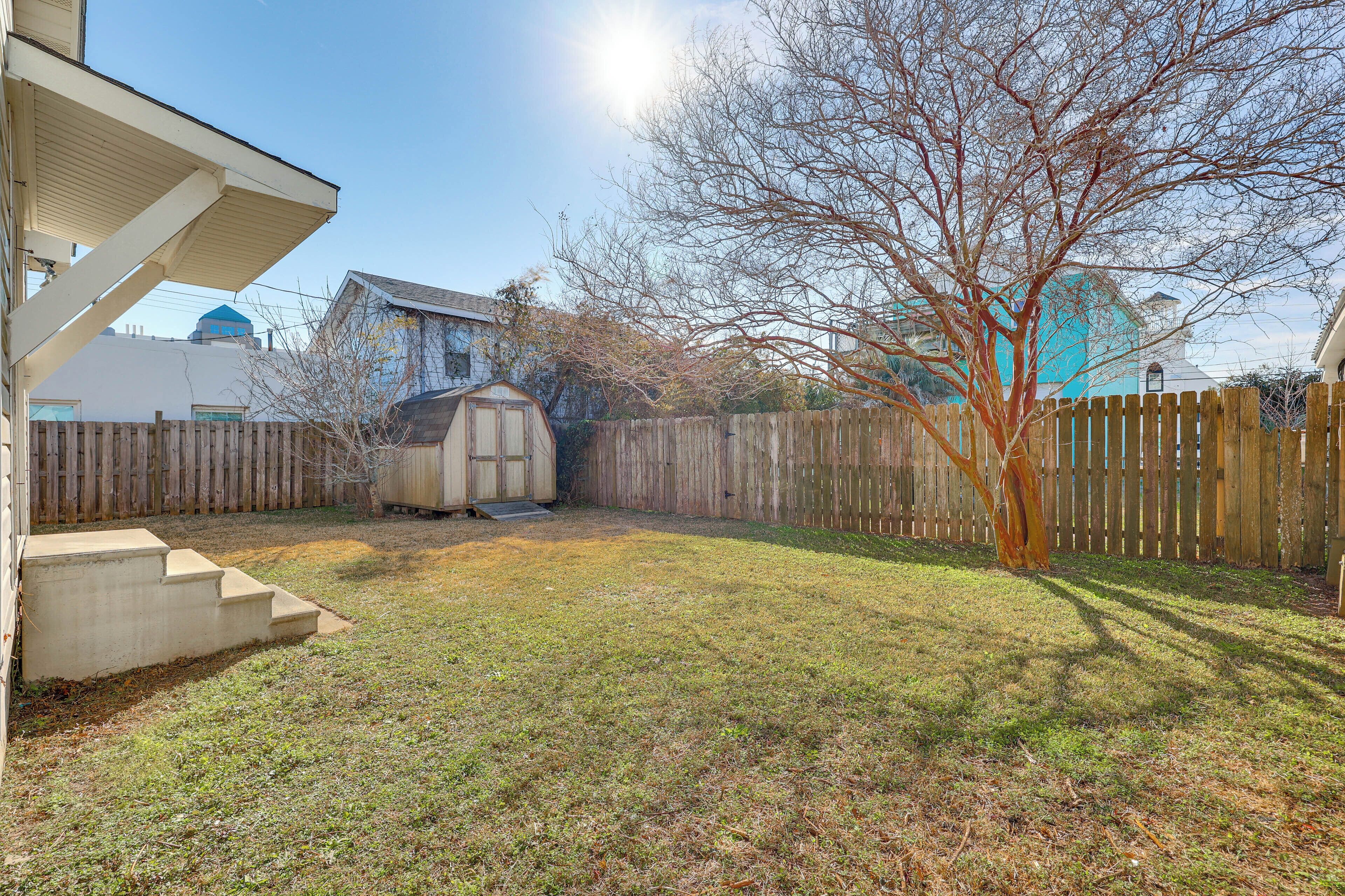 A backyard with a wooden fence, a tree, and a shed.