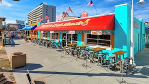 A beachfront restaurant with outdoor seating and American flags. - Steps to Boardwalk: 2 Blocks From the Beach Access (Carolina Beach)