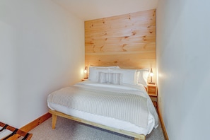 A bedroom with a wooden headboard, a bed with white bedding, and two bedside lamps. - All-season Lake House Between Okemo & Killington! (Plymouth)