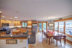 A spacious kitchen with granite countertops, wooden cabinets, and a stainless steel refrigerator.