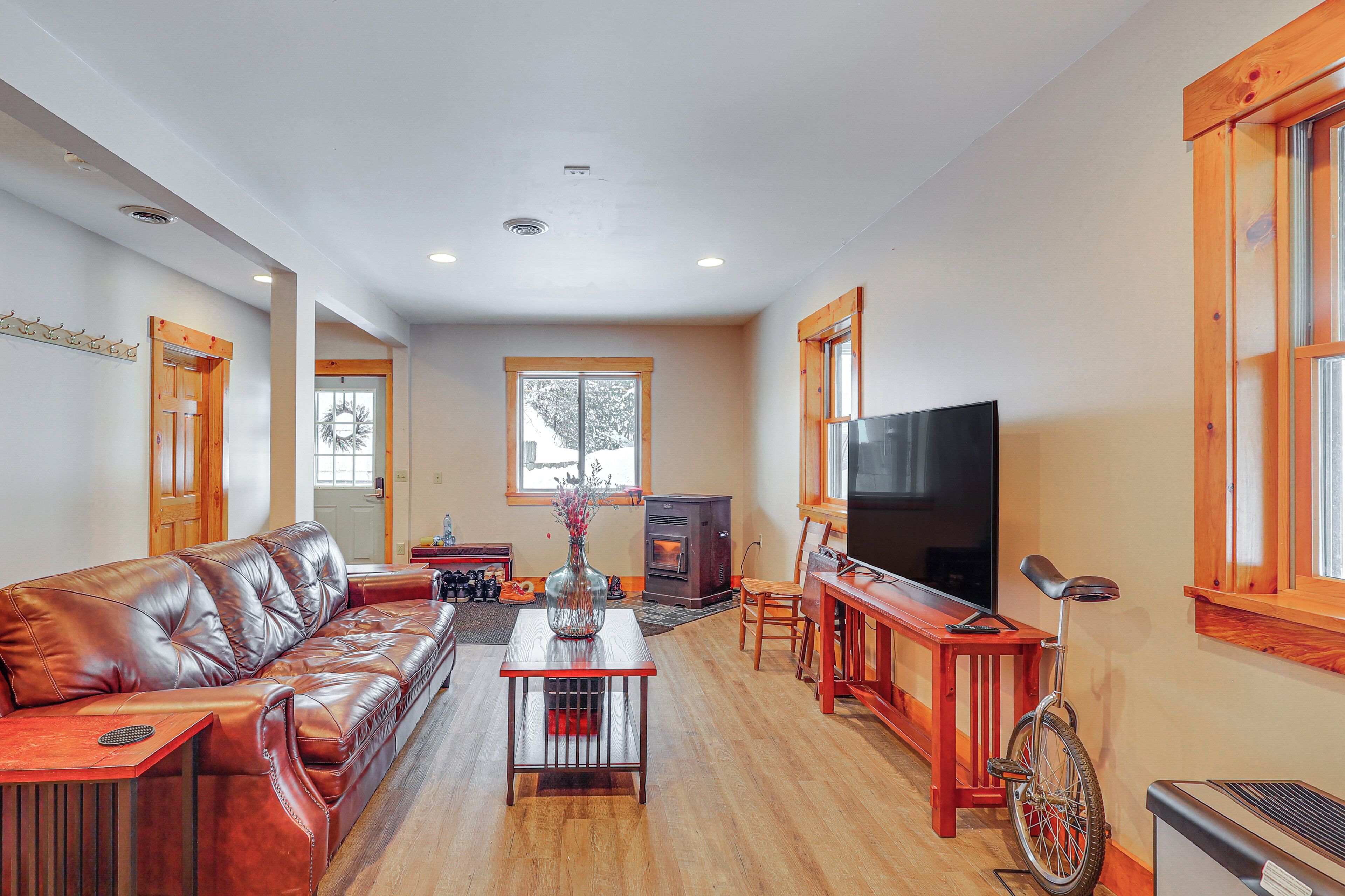 Un salon spacieux avec un canapé en cuir, une table basse en bois, un téléviseur et un vélo.