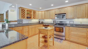 A kitchen with wooden cabinets, granite countertops, a central island, and stainless steel appliances. - All-season Lake House Between Okemo & Killington! (Plymouth)