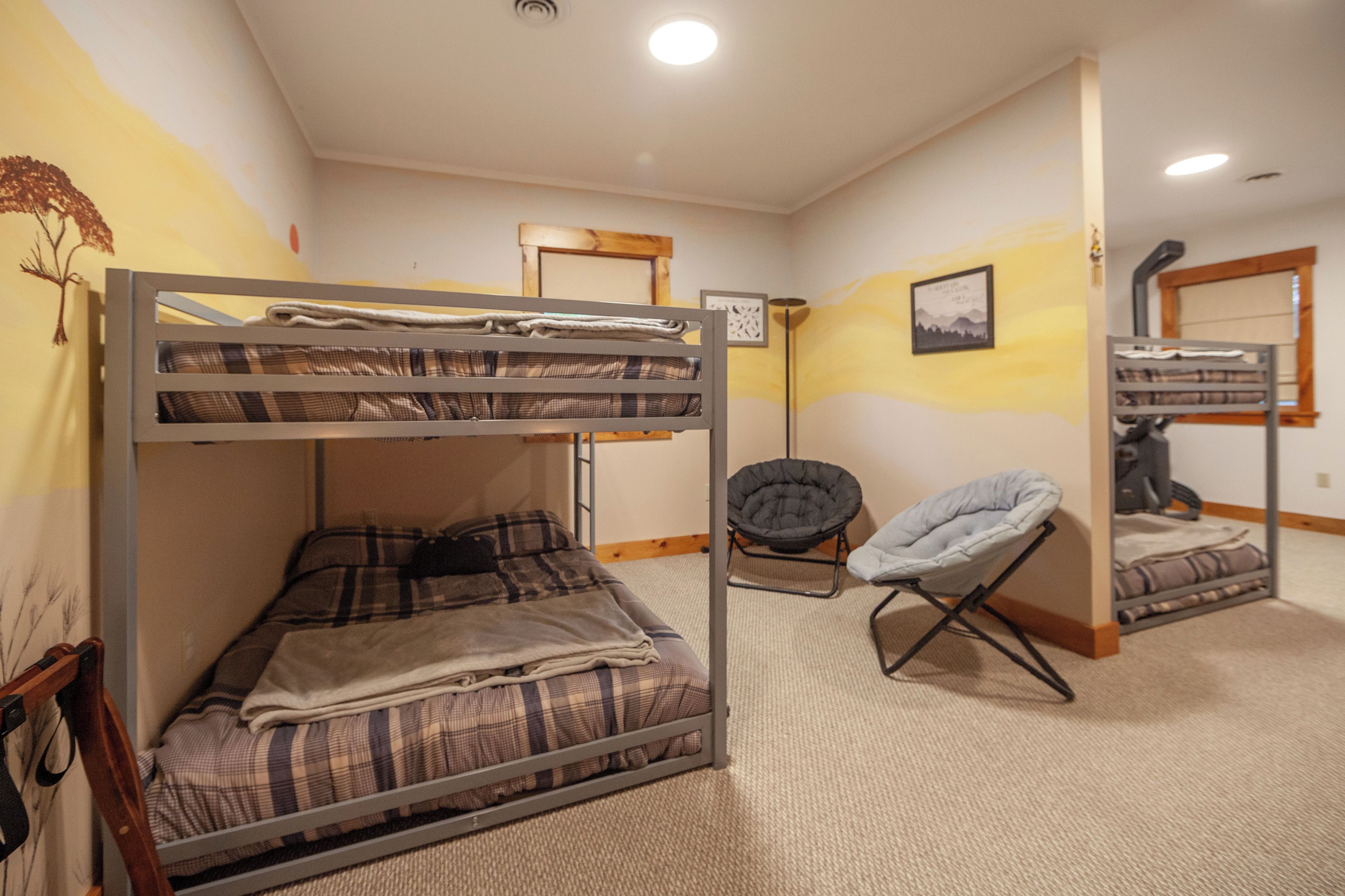 A bunk bed with a plaid blanket, a chair, and a framed picture on the wall.