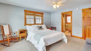 A bedroom with a bed, a rocking chair, a nightstand, a wooden door, and a ceiling fan. - All-season Lake House Between Okemo & Killington! (Plymouth)