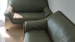 Esquina de una habitación con un sofá de cuero verde y una cortina azul.