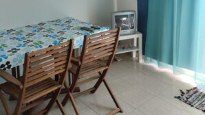 Una habitación con una mesa, sillas, un televisor y una cortina.