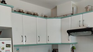 Una cocina con armarios blancos, un refrigerador, una cafetera y un lavamanos.