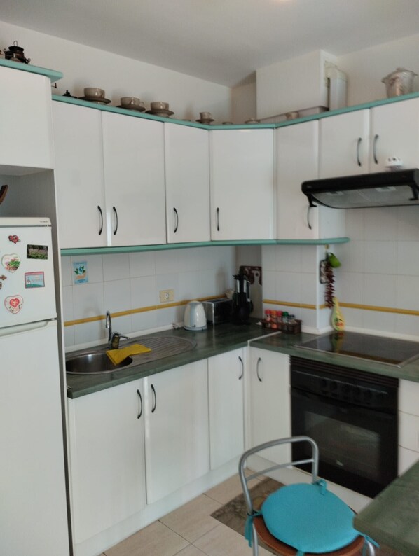 Eine Küche mit weißen Schränken, einem Kühlschrank, einer Kaffeemaschine und einem Spülbecken.