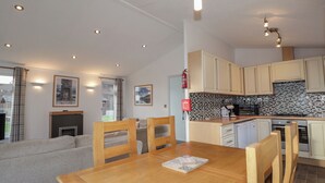 A compact kitchen with modern appliances, a dining area with a wooden table, and a cozy living space with a sofa.