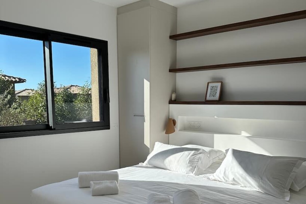 A bedroom with a large bed, a window, and a headboard with shelves.