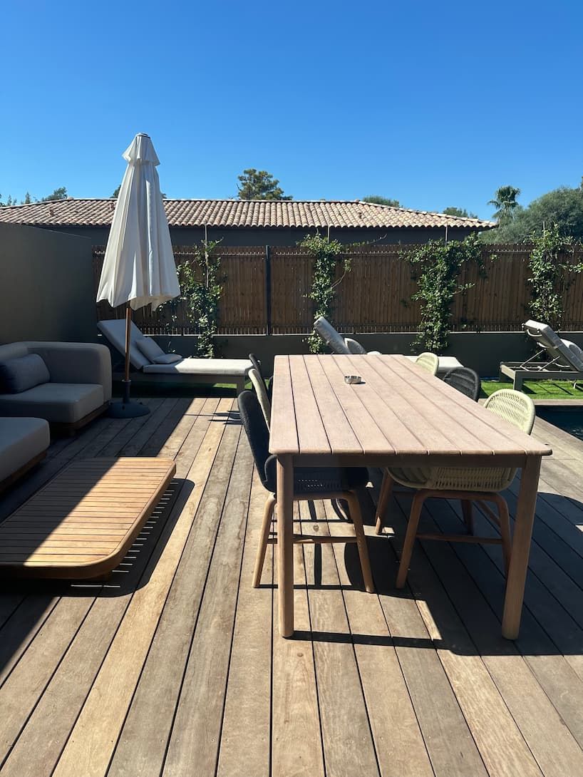 A wooden deck with a table and chairs, a sofa, and an umbrella.