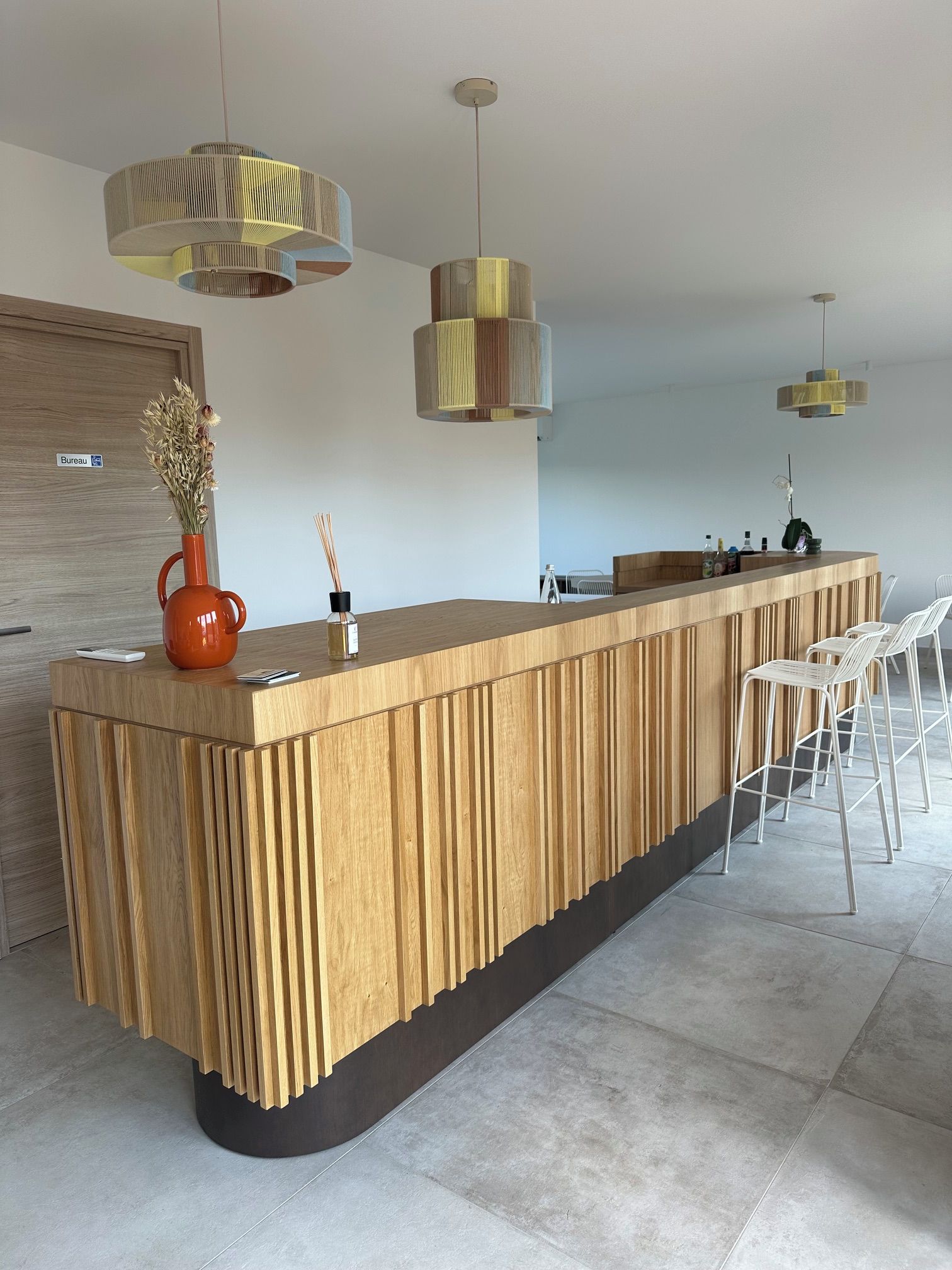 A modern kitchen with a wooden island, pendant lights, and bar stools.
