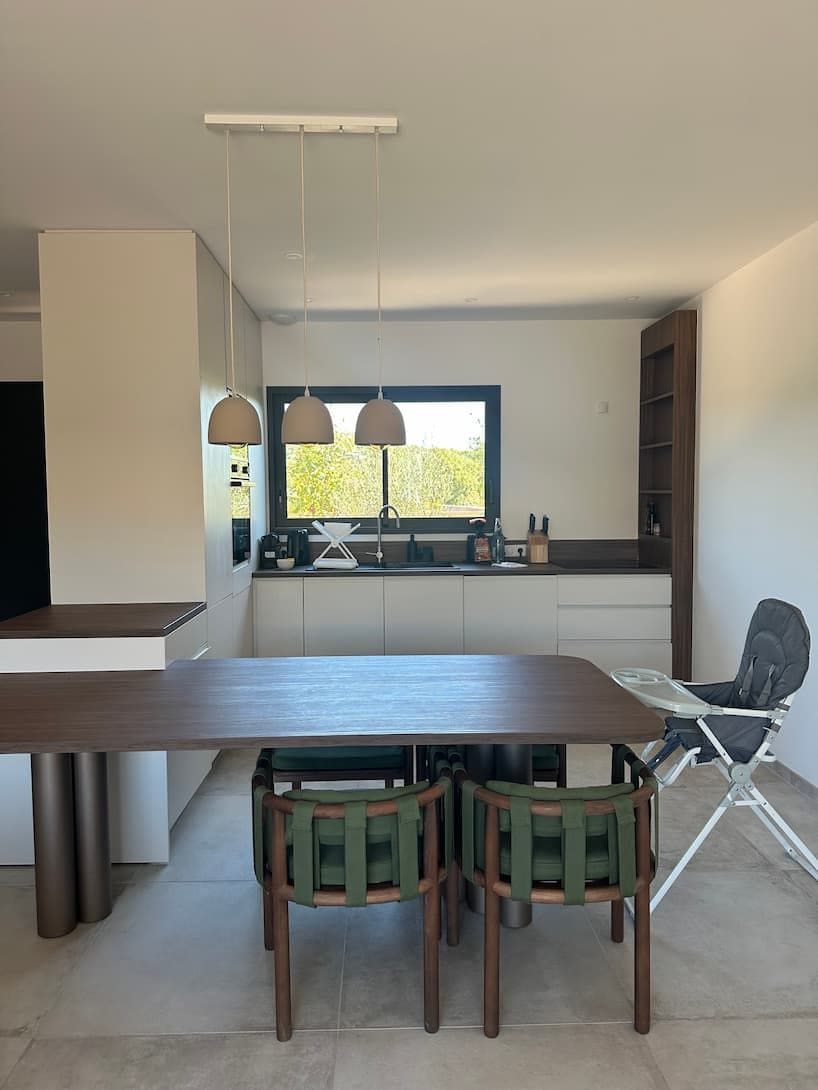 Una cocina moderna con una mesa de comedor y sillas, una ventana con vistas, y una estantería empotrada.