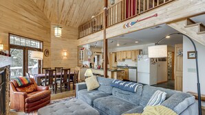 A spacious living area with a large gray sectional sofa, a leather armchair, and a wooden ceiling.