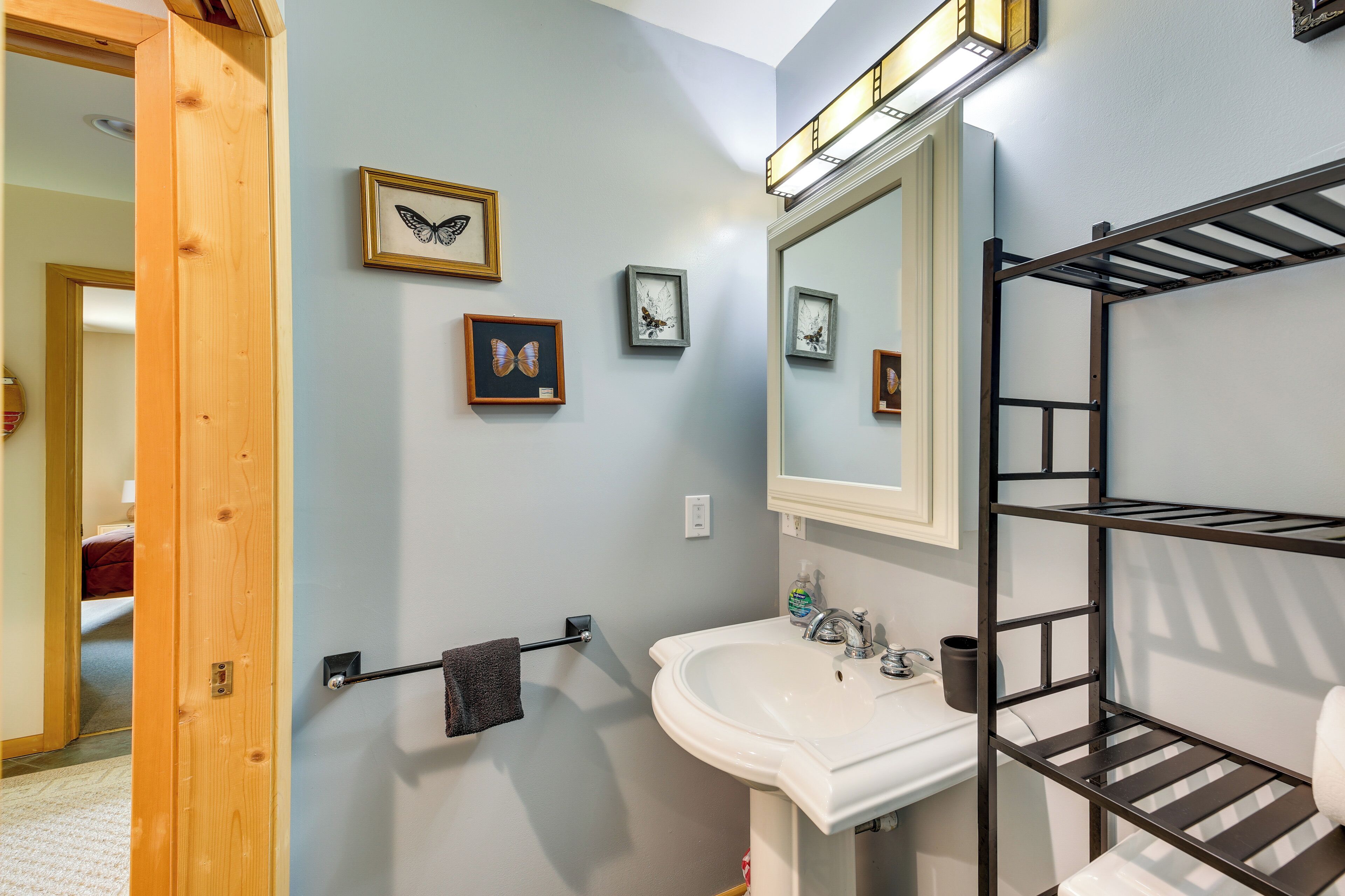 A bathroom with a sink, mirror, and a towel rack.