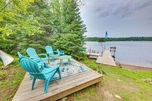 A wooden deck with outdoor furniture, a view of a lake, and a dock extending into the water. - 4-season Recreation: Secluded Pike River Cabin (Tower)