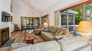 A spacious living room with a fireplace, a dining area, and a large sliding glass door leading to a deck. - Relaxing Bayside Retreat in South Bethany w/ Porch, Bikes & Beach Access (South Bethany)