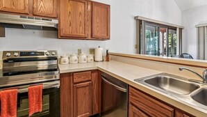 A kitchen with wooden cabinets, stainless steel appliances, a large window, and a sink. - Relaxing Bayside Retreat in South Bethany w/ Porch, Bikes & Beach Access (South Bethany)