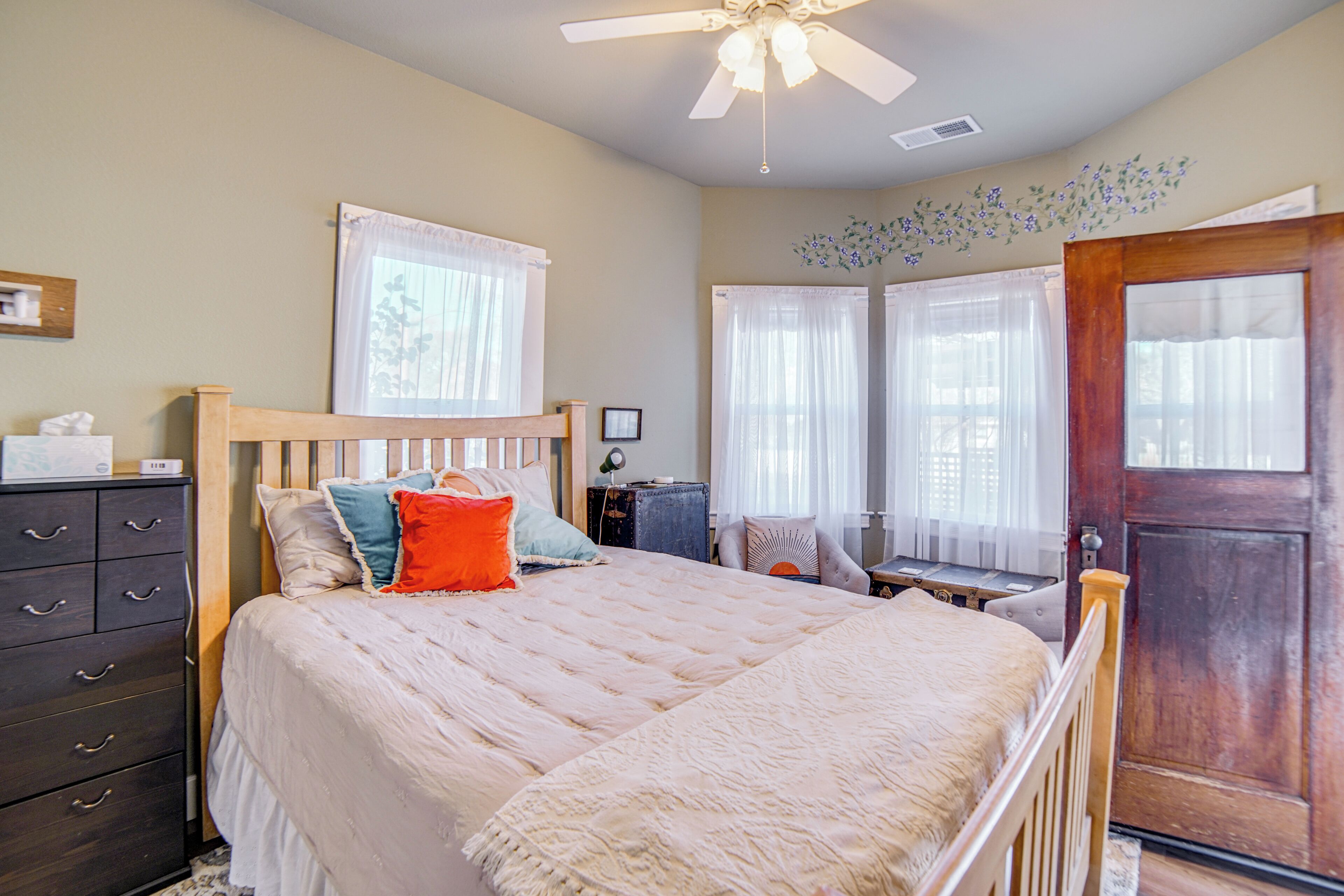 A bedroom with a bed, dresser, and a door.