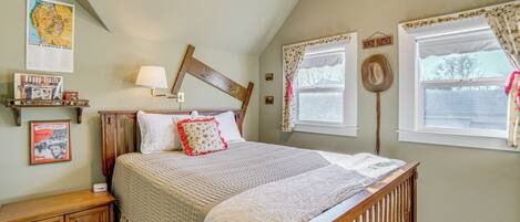 A bedroom with a large bed, a wooden headboard, a ceiling fan, and a window with curtains.